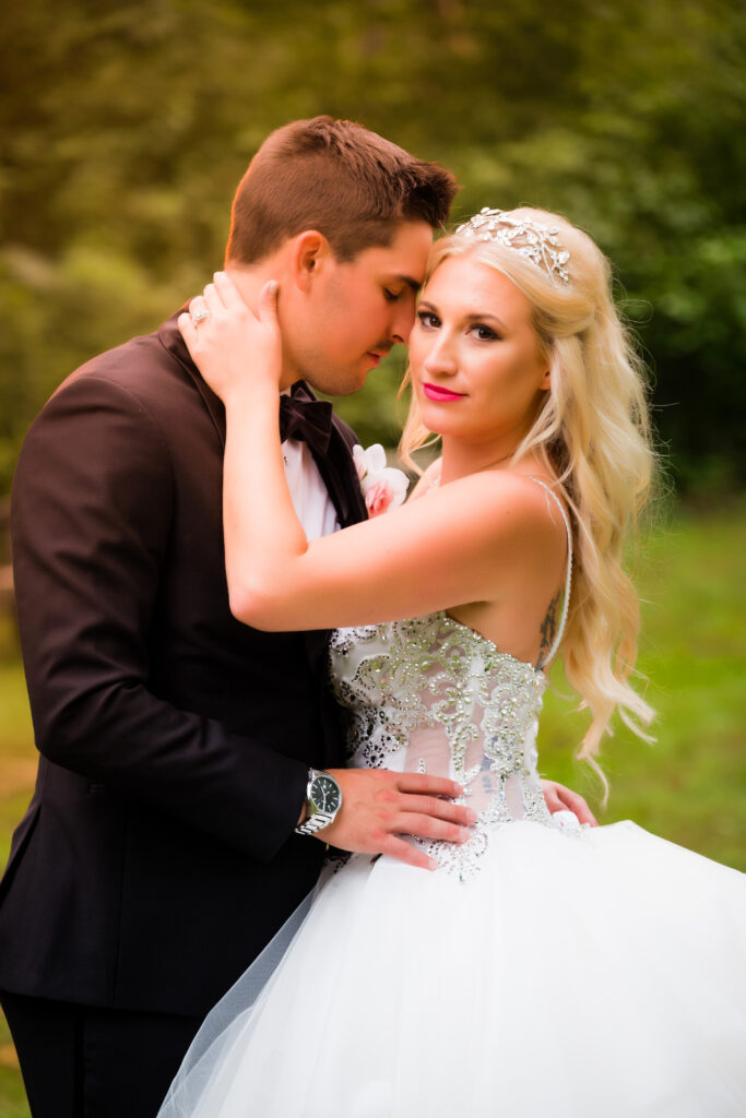 A bride and groom embrace in a lush, green outdoor setting