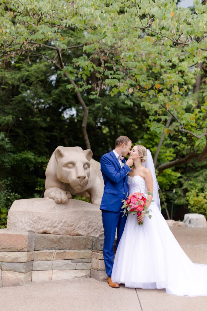 A bride and groom share a tender moment in front of a stone lion statue