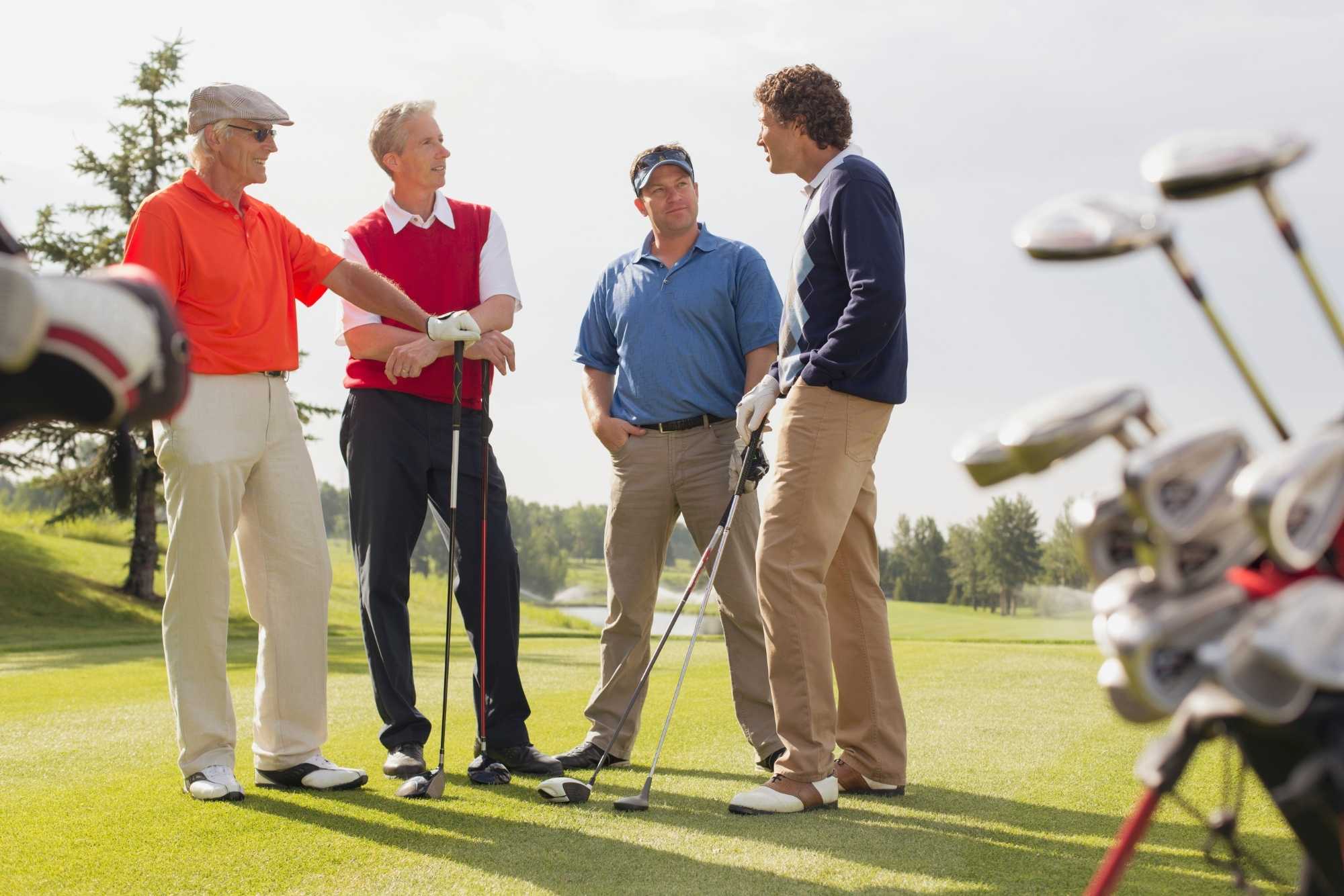 Four men stand on a golf course