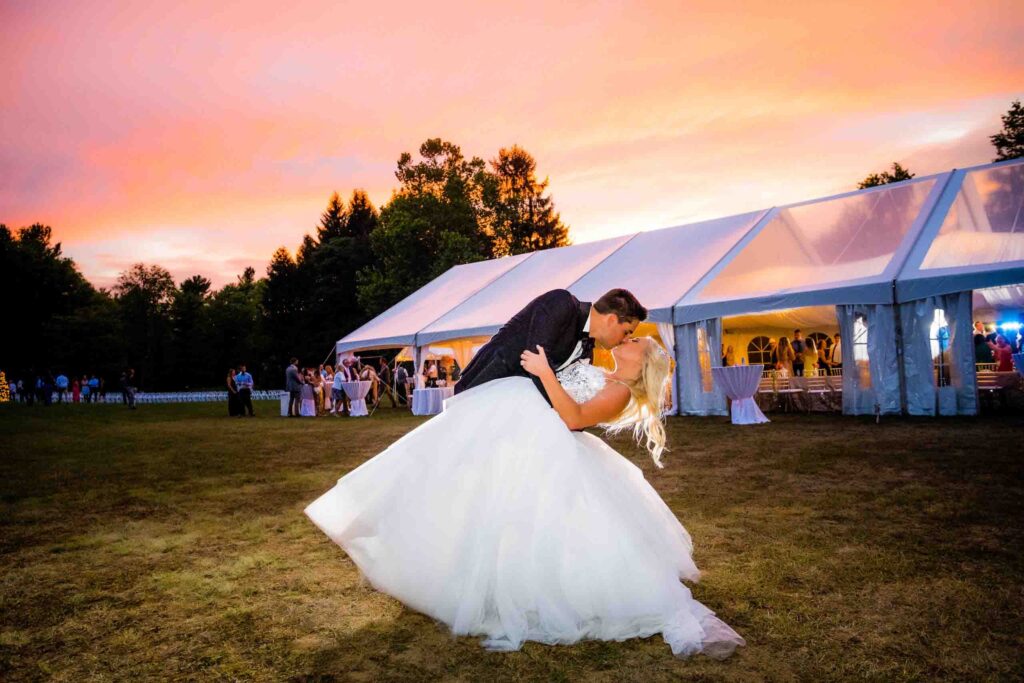 bride and groom kissing in front of sunset