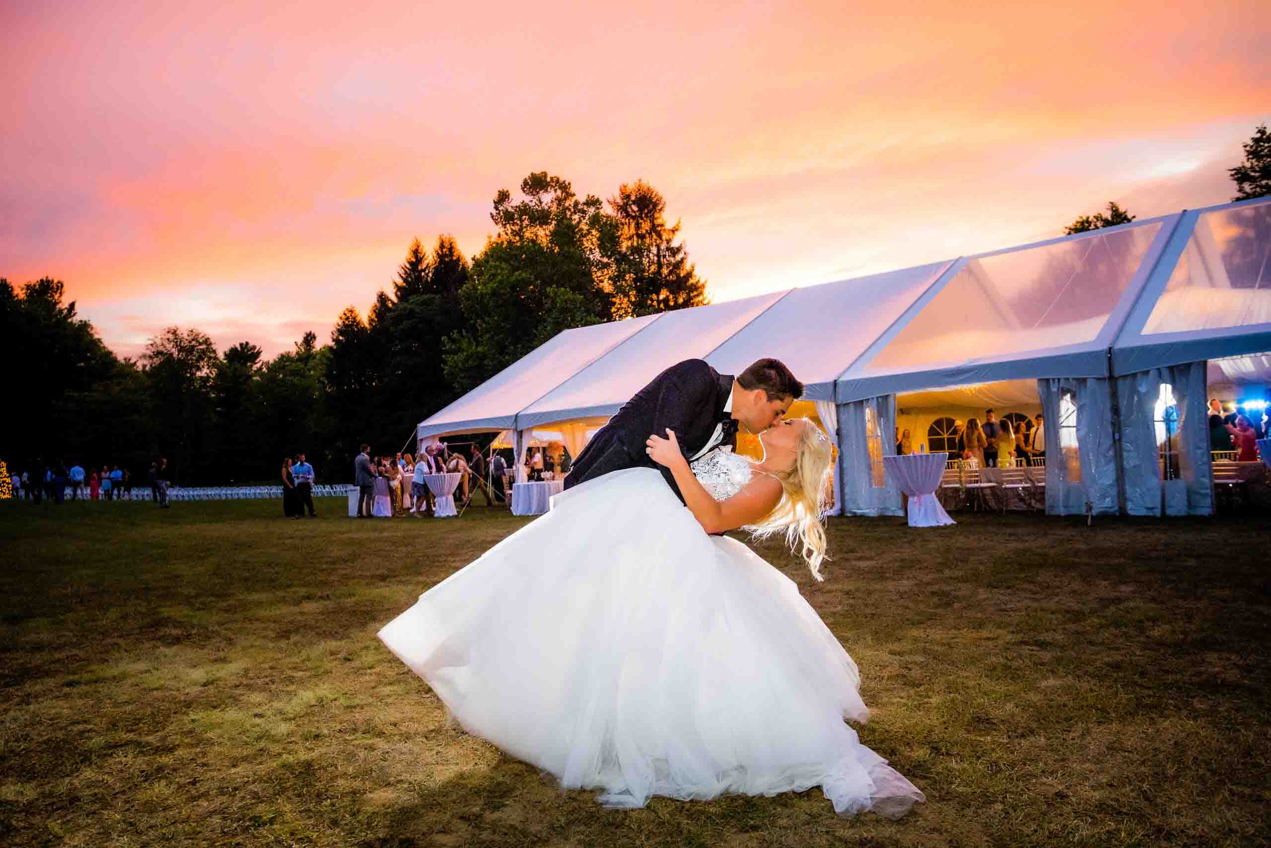 bride and groom kissing in front of sunset