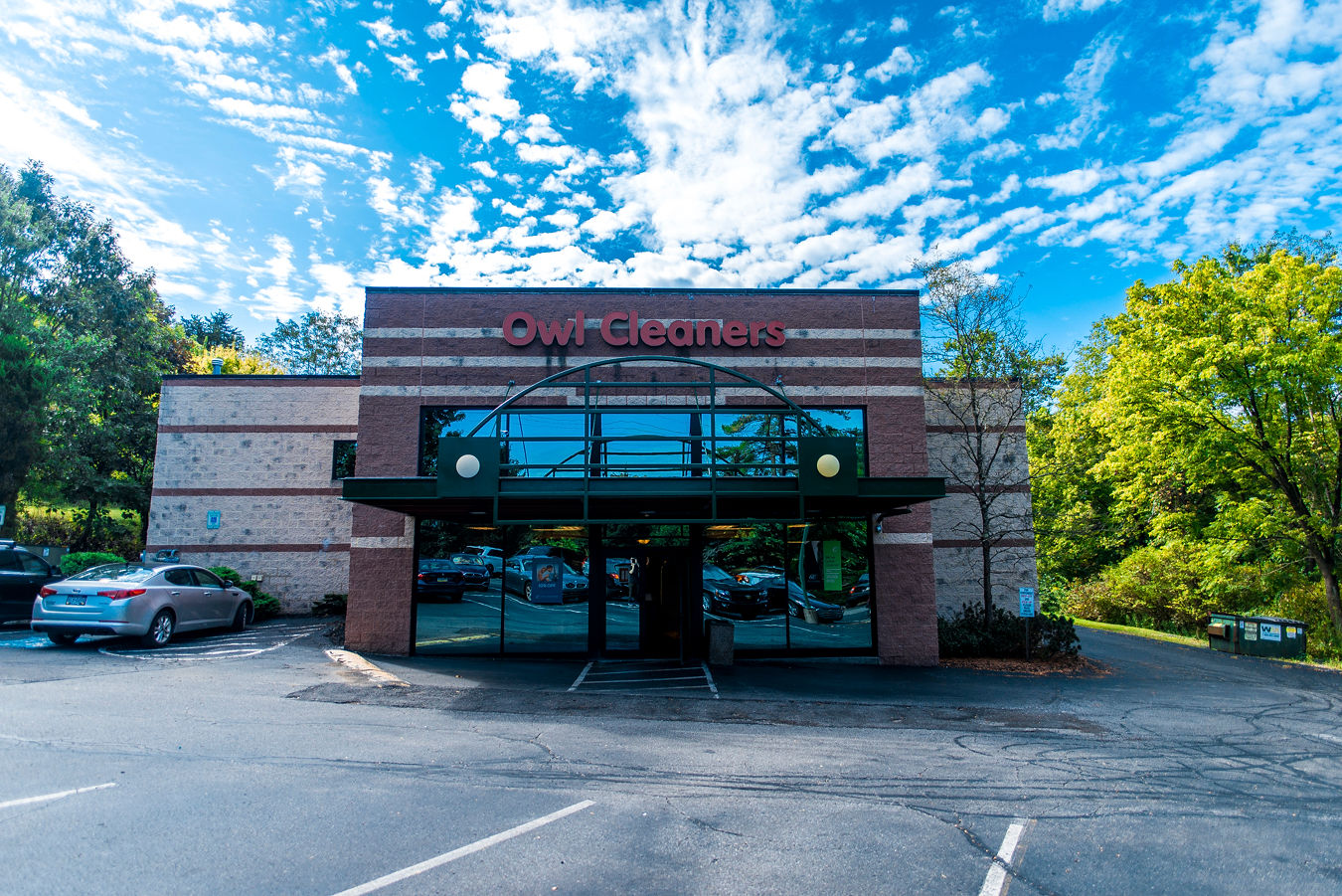 The image shows the entrance of a building labeled "Owl Cleaners" with a brick facade and large glass windows